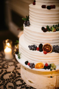 Natural Woods Inspired Wedding Reception Dessert Table with Four Tiered Round White Wedding Cake with Citrus, Berry, and Jewel Toned Florals on Birch Wood Tree Round Cake Stand