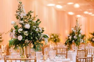 White and Greenery Ballroom Wedding Reception Tall Centerpiece in Gold Candelabra, Small Votive Candles, and Gold Chiavari Chairs