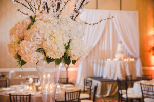 Hotel Ballroom Gold and White Wedding Reception Round Table Decor with Tall White Hydrangea, Pussy Willow Branches and Greenery Centerpiece in Clear Glass Vase with votive candles and blush linens | St Pete Historic Wedding Venue The Vinoy