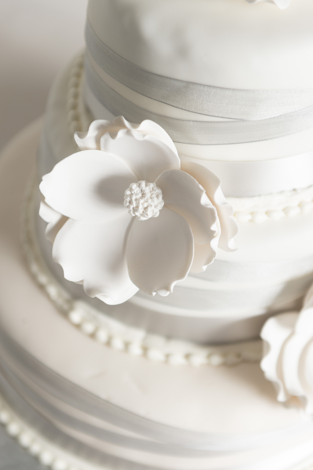 Three Tier White Wedding Cake with White Fondant Flowers, Silver Ribbon, on Silver Cake Stand