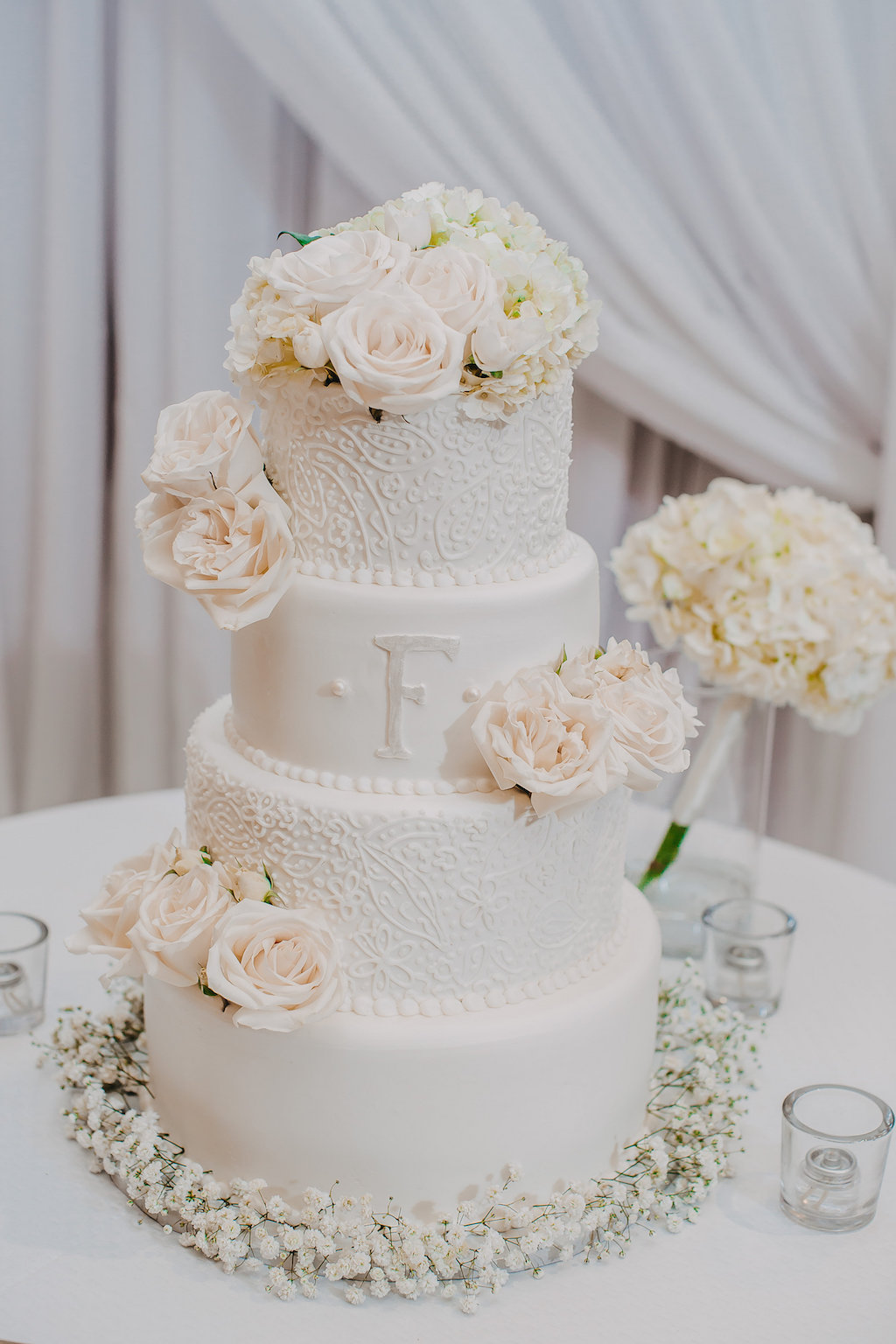 Four Tier Round White Wedding Cake with Initial and Floral Icing, Blush Roses, and White Floral Cake Stand
