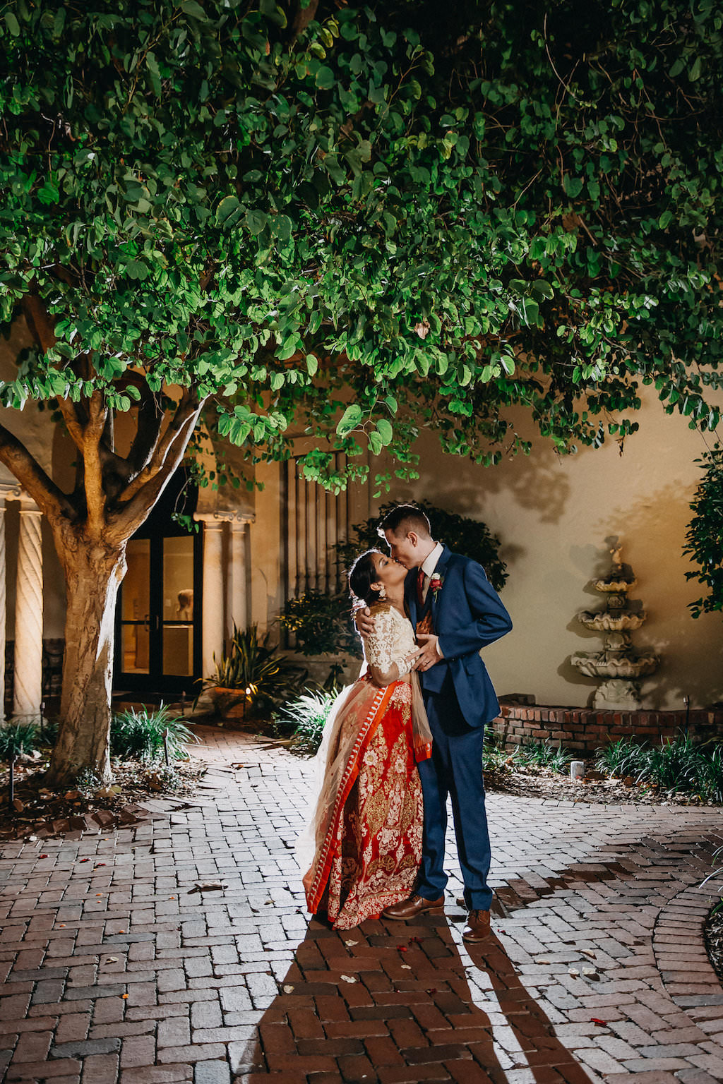 Modern Indian Wedding Courtyard Garden Nighttime Outdoor Wedding Portrait, Bride in Red and Gold with White Saree, Groom in Blue Suit | St Pete Wedding Photographer Rad Red Creative | Venue St Petersburg Museum of Fine Arts | Menswear Sacino's Formalwear