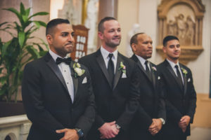 Groom and Groomsmen Wedding Ceremony Portrait in Black Tuxedos with White Rose with Greenery Boutonniere
