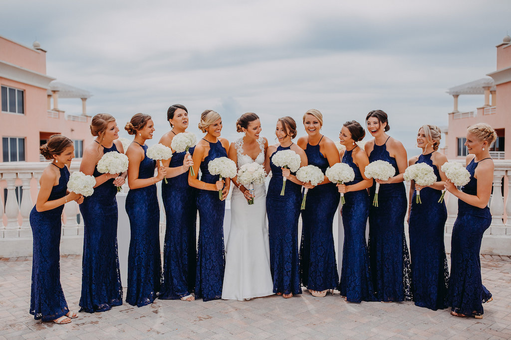 Outdoor Rooftop Bridal Party Portrait, Bridesmaids in Halter Navy Blue Column Lulu's Zenith Dresses, Bride in Lace Cap Sleeve A Line Sincerity Bridal Wedding Dress, with White Floral Bouquet | Tampa Bay Wedding Photography Rad Red Creative | Waterfront Hotel Wedding Venue Hotel Venue Hyatt Regency Clearwater Beach