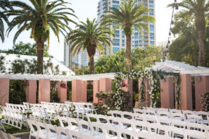 Outdoor Historic Hotel Courtyard Wedding Ceremony with White Folding Chairs and White Floral and Greenery Chuppah Wedding Arch | St Pete Wedding Venue The Vinoy
