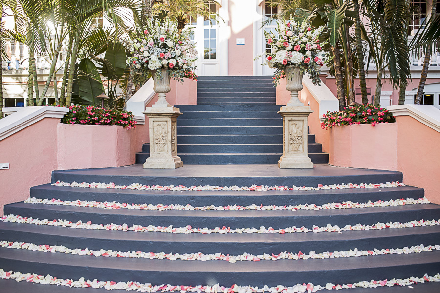 Tropical Hotel Wedding Ceremony Decor with White and Pink Rose Petals on Steps, and Large Peach, White, and Greenery Florals in Classic Stone Planters on Columns | St Pete Beach Hotel Wedding Venue the Don CeSar