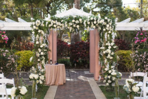 Outdoor Garden Courtyard Jewish Wedding Ceremony with Tall White and Greenery with Natural Branches Flowers, and White Floral and Greenery Garland Chuppah Wedding Arch | St Pete Wedding Venue The Vinoy