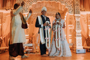 Regal and Romantic Traditional Hindu Indian Wedding Reception Bride and Groom Portrait with Gold Uplighting and Blush Pink Draping Behind the Mandap | Tampa Bay Wedding Venue Safety Harbor Resort and Spa | Planner Glitz Events | Photographer Grind and Press Photography