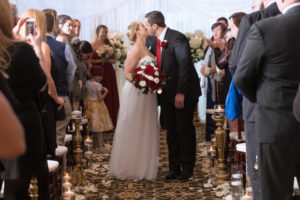 Wedding Ceremony First Kiss Portrait, Bride holding Red and WHite Rose with Greenery Bouquet, Groom with Red Tie and Red Rose Boutonniere | Tampa Wedding Photographer Carrie Wildes Photography