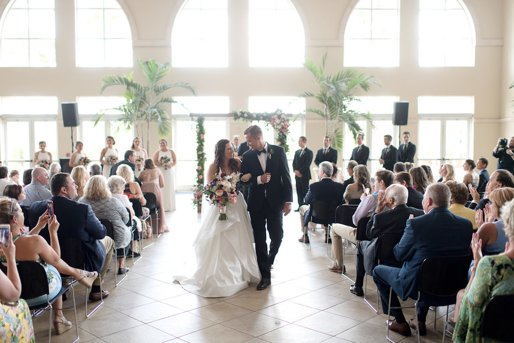 Indoor Church Ceremony Exit Portrait with Floral Arch with Peach Roses, White and Purple and Pink Flowers with Greenery, and Palm Trees | Lutz FL Wedding Ceremony Venue Idlewild Baptist Church