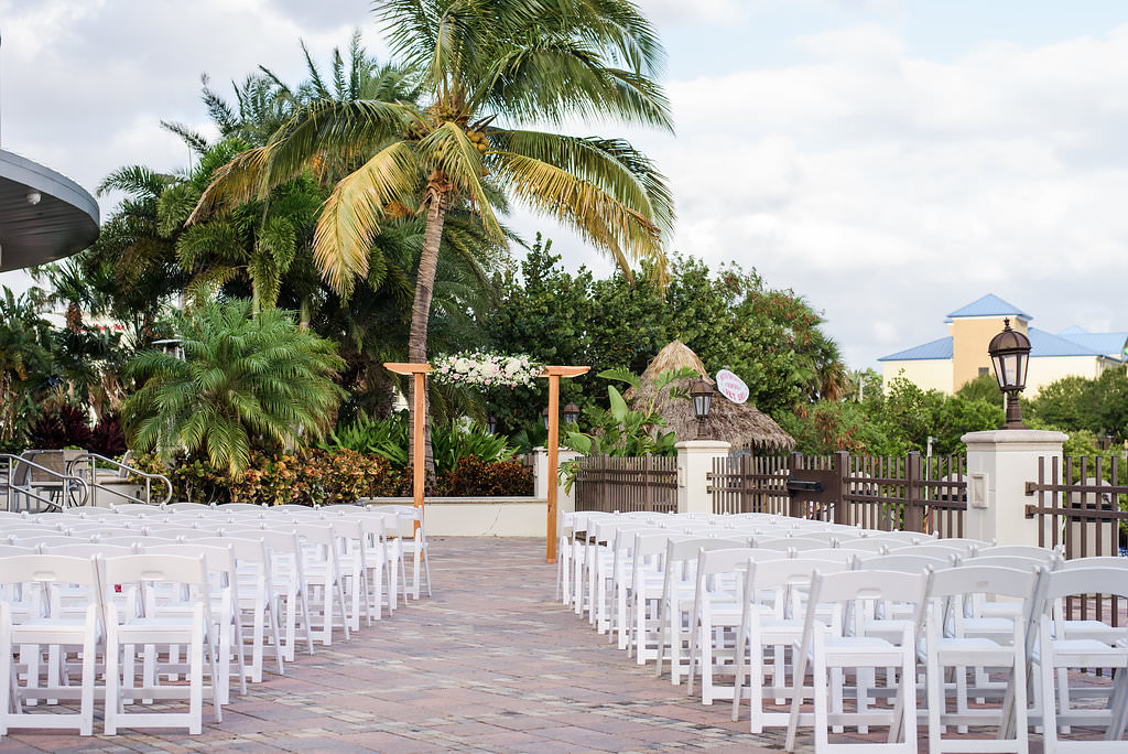 Outdoor Wedding Ceremony with Wooden Ceremony Arch with White Flowers and Greenery, and White Folding Chairs | Waterfront Hotel Wedding Venue The Westin Tampa Bay