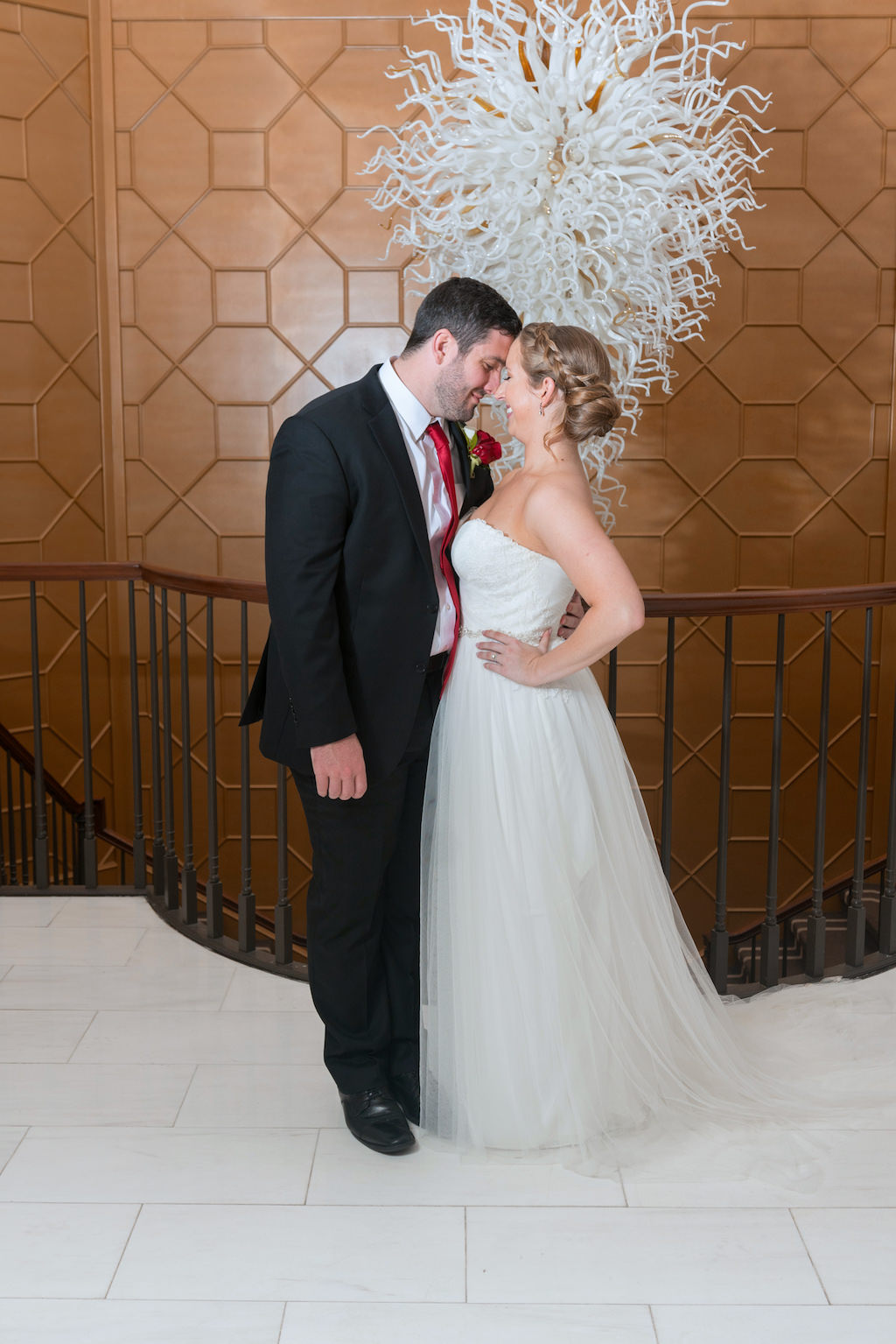Indoor Wedding Portrait with Glass Chandelier, Bride in Strapless A Line Maggie Sottero Dress, Groom with Red Tie and Red Rose Boutonniere | Tampa Bay Wedding Photographer Carrie Wildes Photography | Downtown Wedding Venue The Tampa Club