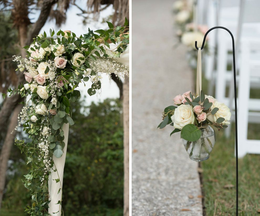 Outdoor Garden Wedding Ceremony Decor Details with Hanging GLass vase with Ivory ROse and Pink Floral with Greenery in Glass Vase, White Folding Chairs, and Natural Greenery and White Flower Ceremony Arch