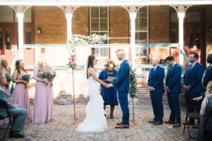 Outdoor Wedding Ceremony Portrait, Bride in Mermaid Enzoani Dress, Bridesmaids in Blush Pink Azazie Dresses, Groomsmen in Blue Suits with Minimalist Arch with Pink and White Rose with Greenery Decor | Ybor City Historic Architecture Wedding Venue CL Space | Tampa Wedding Photographer Kera Photography