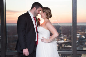 Indoor Wedding Portrait with Tampa Skyline, Bride in Strapless A Line Maggie Sottero Dress, Groom with Red Tie and Red Rose Boutonniere | Tampa Bay Wedding Photographer Carrie Wildes Photography | Downtown Wedding Venue The Tampa Club
