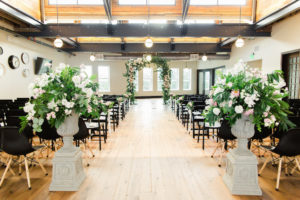 Indoor Industrial Garden Wedding Ceremony Decor with Floral and Greenery Arch, White and Blush Flower with Natural Greenery in Tall Planter, and Mismatched Dark Wooden Chairs | Tampa Bay Venue The Oxford Exchange