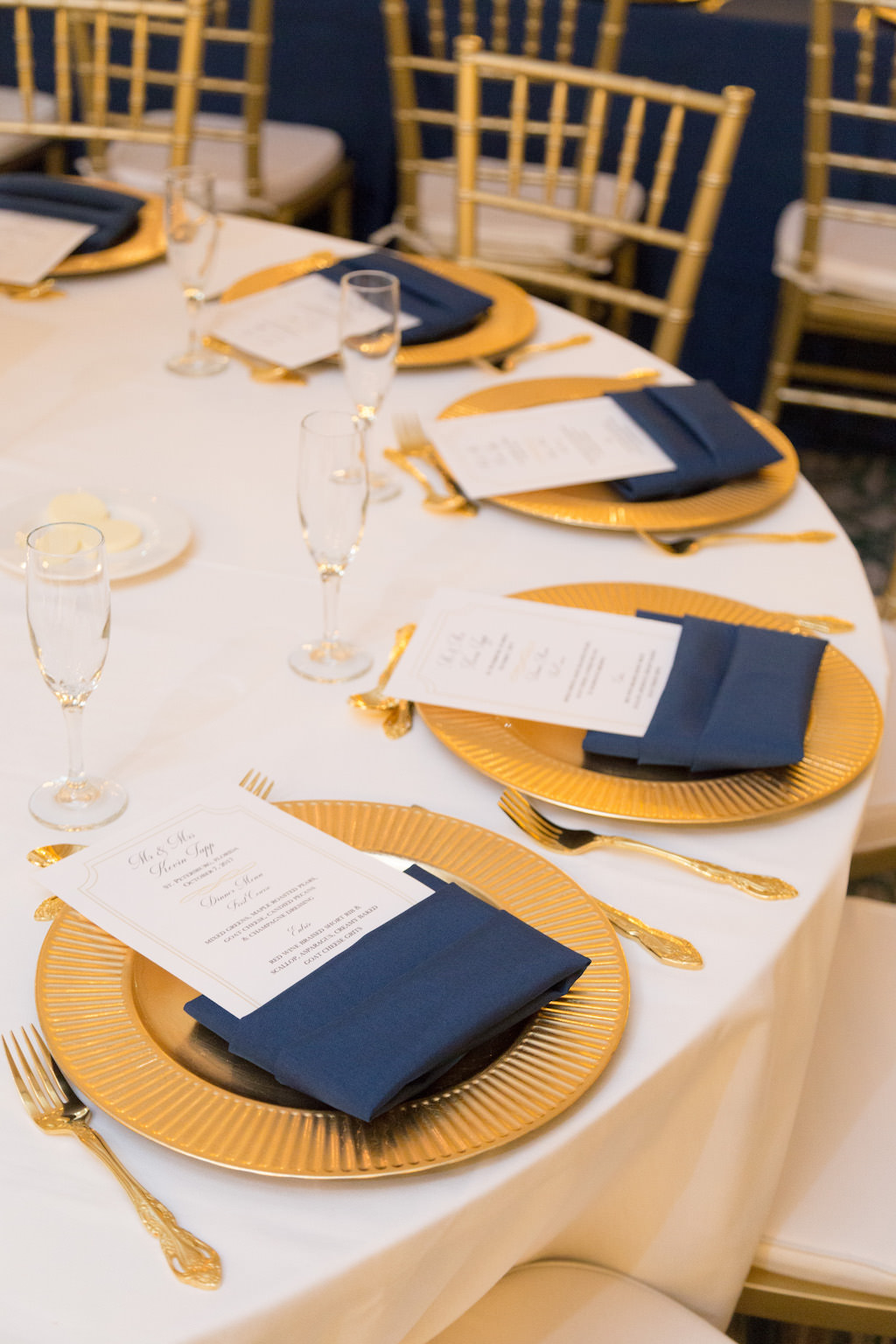 Southern Elegance Wedding Reception Round Table Setting with Gold Chargers, White Printed Menus in Navy BLue Napkins, Blush Linens, and Gold CHiavari Chairs and Flatware