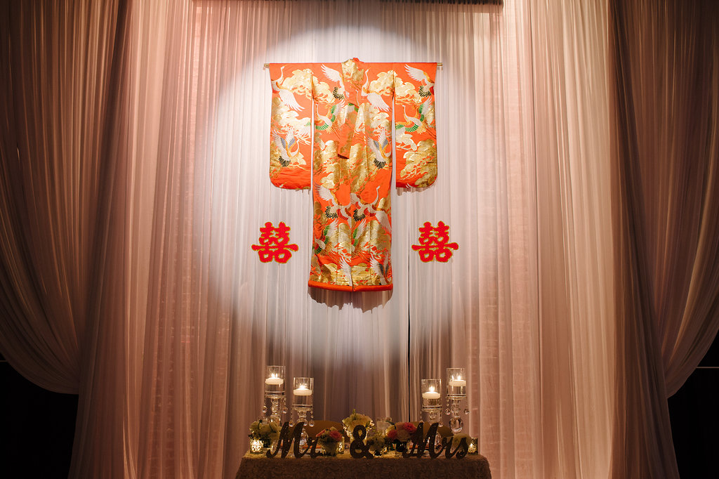 Multicultural Wedding Reception Sweetheart Table with Hanging Traditional Chinese Wedding Dress and Characters, White Draping, Oversized Votive Candles in Glass Holders and Mr and Mrs Signs | Downtown St Pete Wedding Reception Venue NOVA 535