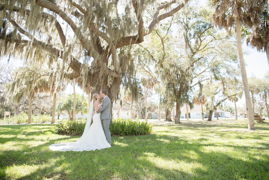 Outdoor Garden Bride and Groom Wedding Portrait, Groom in Gray Suit, Bride in Lace Trumpet Allure Bridals Dress | Sarasota Wedding Photographer Kristen Marie Photography | Historic Venue The Edson Keith Mansion