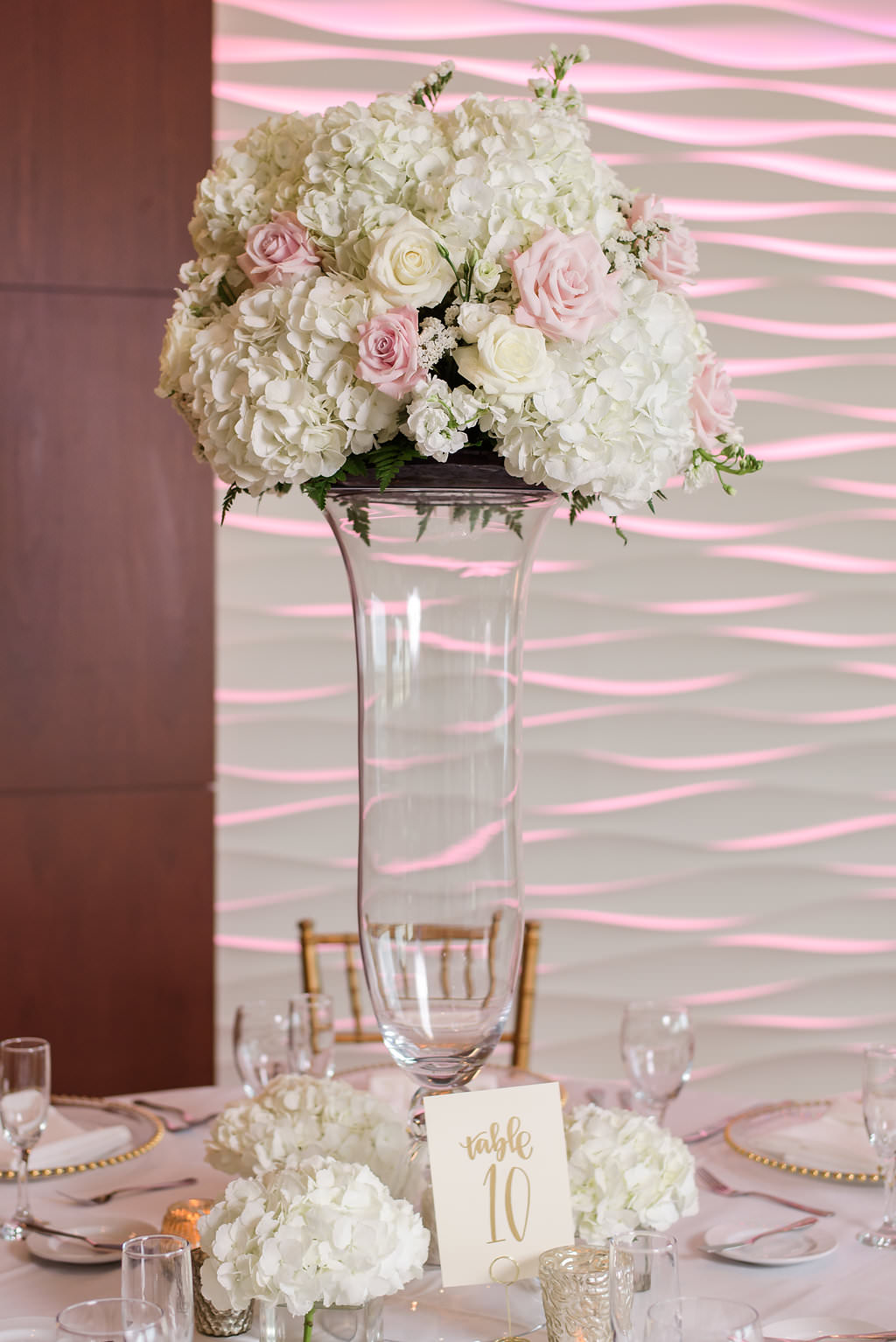 White and Gold Wedding Reception with Tall White Hydrangea, Rose, and Blush Pink Rose Centerpiece in Glass Vase, and Stylish Gold Printed Table Number on Square White Paper