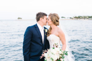 Outdoor Downtown St. Pete Waterfront Wedding Portrait, Bride wearing Lace Sweetheart Strapless Enzoani Wedding Dress with White Floral and Copper and Greenery Bouquet, Groom in Blue Suit with White Boutonniere