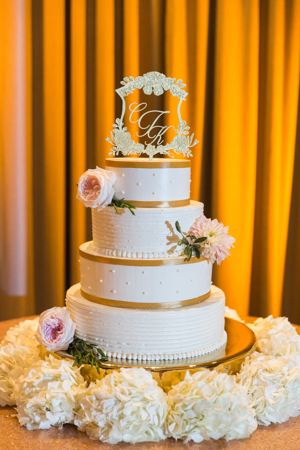 Four Tier Round White with Gold Ribbon Stripes Wedding Cake with Ornate Custom Monogram Floral Framed Cake Topper on Gold Cake Stand with White and Pink Flowers | St Pete Wedding Stationary and Monograms A and P Designs | Historic Hotel Wedding Venue, Caterer, and Cake Vinoy Renaissance
