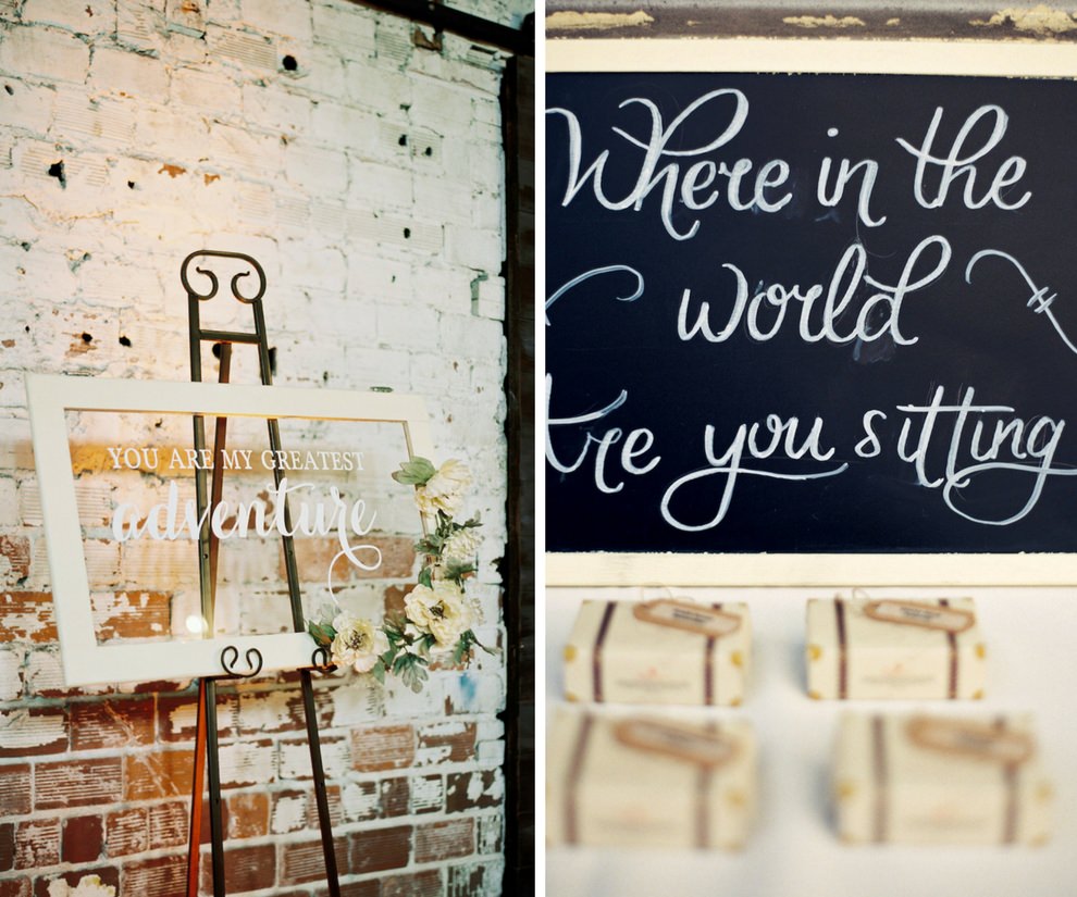 Vintage Travel Inspired Wedding Reception White Framed Clear Glass Welcome Sign with Ivory FLowers and Greenery, and Escort Card Table with Handwritten Chalkboard Sign and MIni Suitcase Favors with Luggage Tag Cards | Tampa Historic Wedding Venue The Rialto Theatre | Planner Glitz Events
