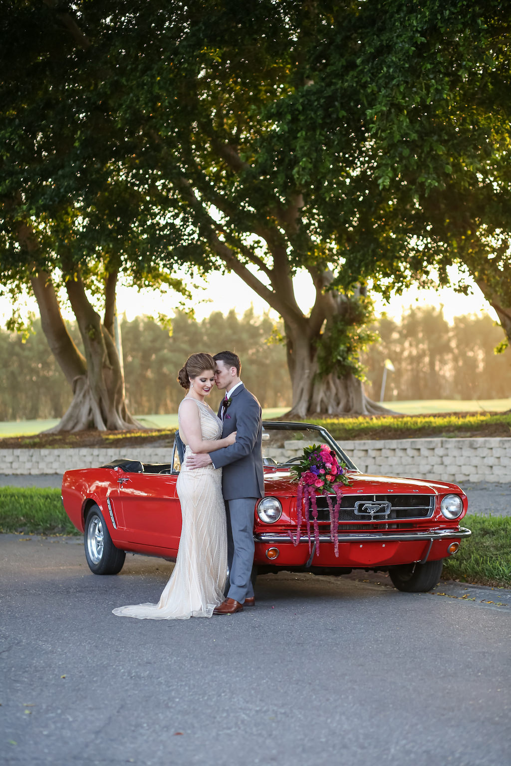Bride and Groom Portrait with Pink, Fuchsia, Purple and Plum with Greenery Cascading Wedding Bouquet on Red Vintage Mustang Classic Car | Tampa Bay Wedding Florist Gabro Event Services | Planner Kelly Kennedy Weddings and Events | Photographer Lifelong Photography Studio