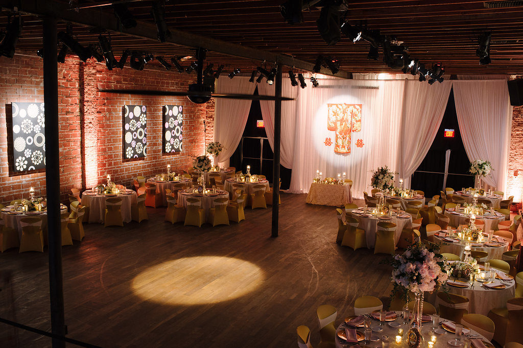 Gold and Pink Multicultural Wedding Reception with White Draping, Hanging Traditional Chinese Wedding Dress and Characters, Round Tables with Satin Linens, Gold Fabric Covered Chairs, Extra Tall Pink FLoral and Greenery Centerpieces in Glass Vases with Hanging Jewels | Downtown St Pete Unique Wedding Reception Venue NOVA 535