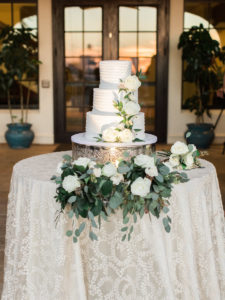 Outdoor Wedding Reception Three Tier Round White Cake with White Roses and Greenery on Textured White Linen | Tampa Wedding Cake Baker Alessi Bakery