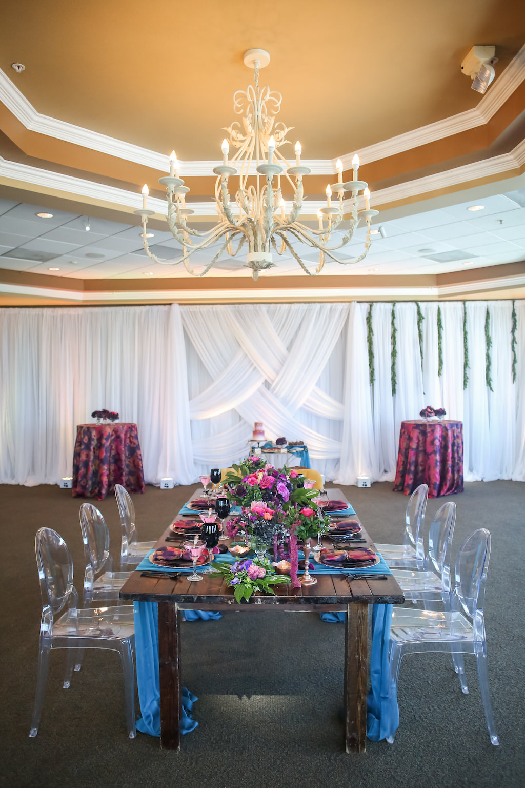 Vibrant, Modern Ballroom Wedding Reception with Rustic Wooden Feasting Table, Turquoise Linens, Low Fuchsia and Greenery Centerpieces, Clear Plastic Chairs, and White Draping | Tampa Bay Wedding Venue Isla Del Sol Yacht and Country Club | Planner Kelly Kennedy Weddings and Events | Draping and Florist Gabro Event Services | Furniture Rentals A Chair Affair