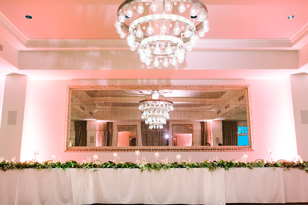 Ballroom Wedding Reception Feastign Table with Greenery Garland and Clear Glass Floating Votive Candle Holders and Chandelier | Downtown St Pete Historic Boutique Hotel Wedding Venue The BIrchwood