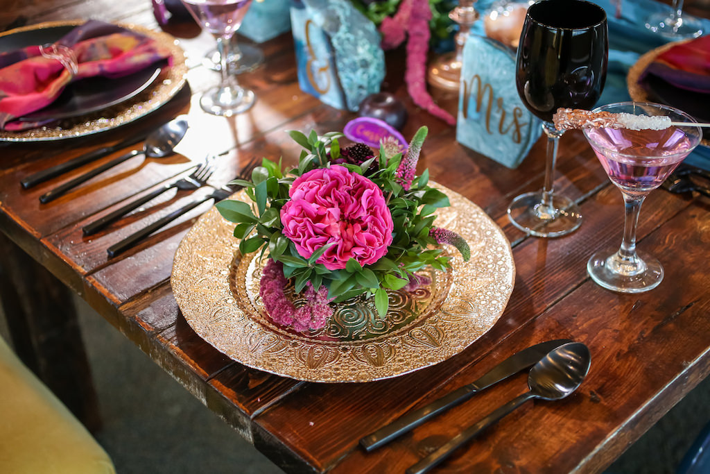 Whimsical Wedding Reception Wooden Feasting Table with Black Flatware, Wine Glasses, and Plates, Copper Chargers and Votive Candleholders, Low Plum and Fuchsia Florals with Greenery Centerpieces, Pink and Purple Watercolor Napkins and Turquoise Linen Runners, Glitter Rock Candy Favors | Tampa Bay Wedding Planner Kelly Kennedy Weddings and Events | Furniture Rentals A Chair Affair | Florist Gabro Event Services