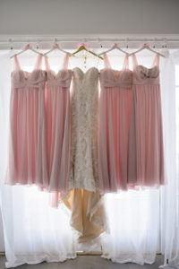 Beach Wedding Bridal Party Dresses on Pink Bow Hangers, with Lace Princess Strapless Essense of Australia Wedding Dress, and Dessy Group Empire Waist Blush Pink Bridesmaid Dresses with Straps