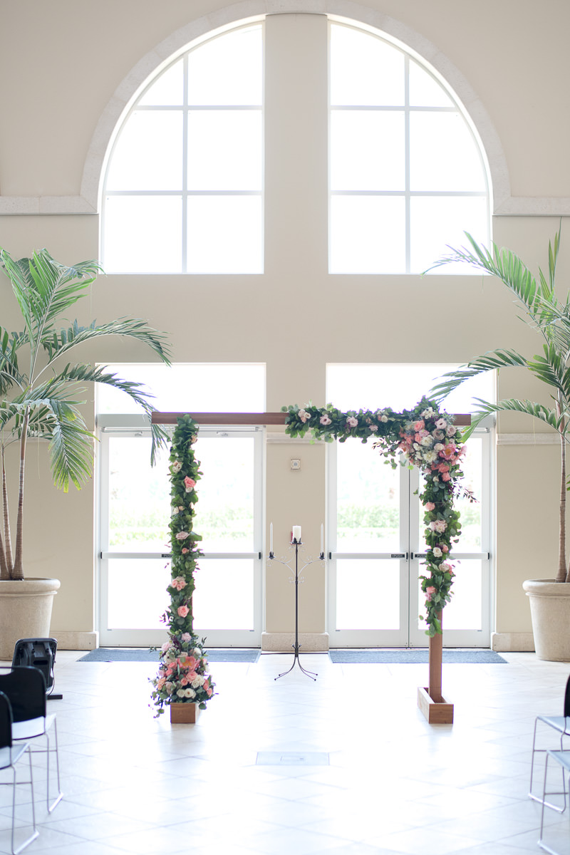 Indoor Church Ceremony Wedding Ceremony Floral Arch with Peach Roses, White and Purple and Pink Flowers with Greenery, and Palm Trees | Lutz FL Wedding Ceremony Venue Idlewild Baptist Church