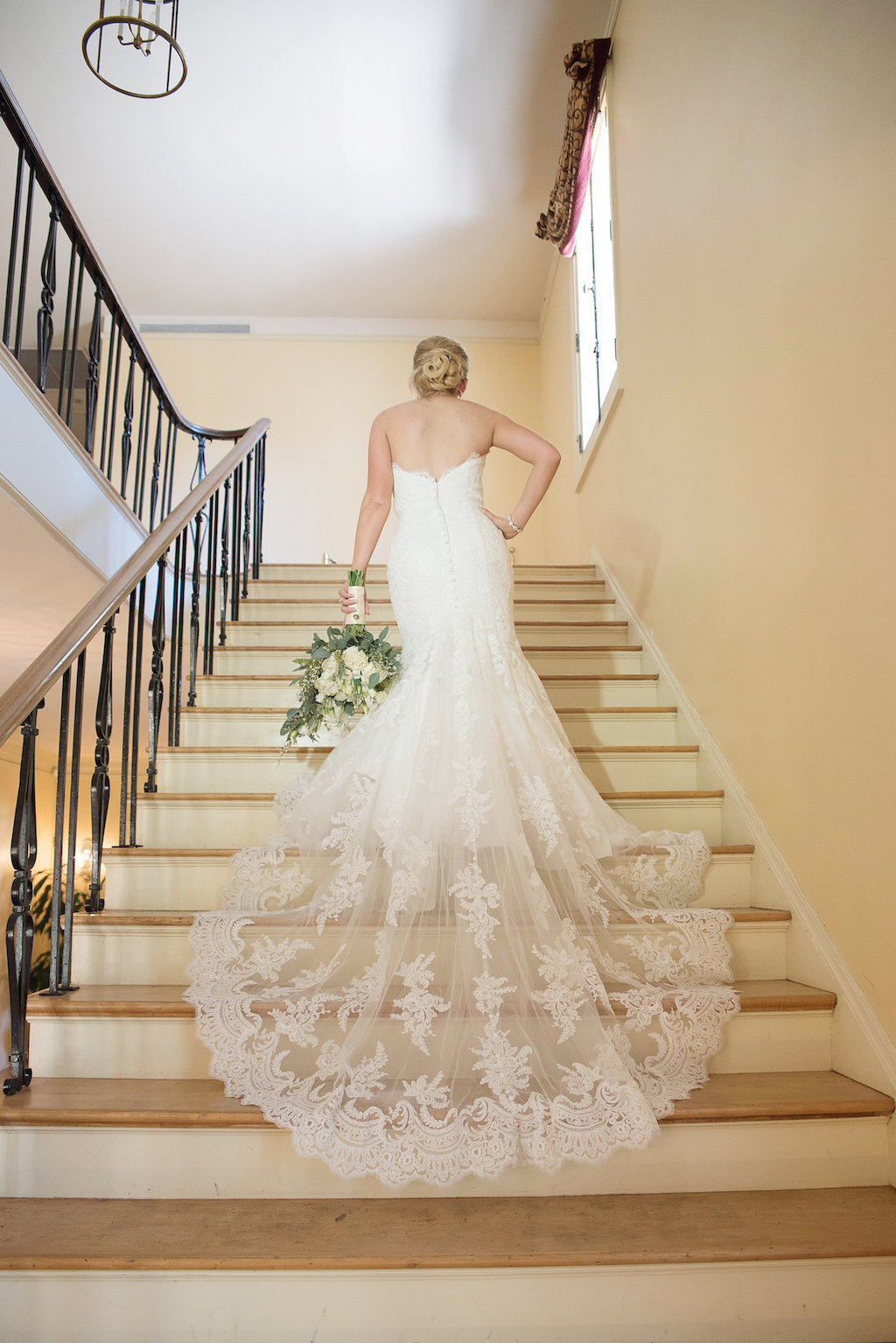 Bride on Staircase wedding Portrait with White and Greenery Bouquet wearing Strapless Lace Train Allure Bridals Wedding Dress | Sarasota Historic Wedding Venue The Edson Keith Mansion | Tampa Bay Wedding Photographer Kristen Marie Photography