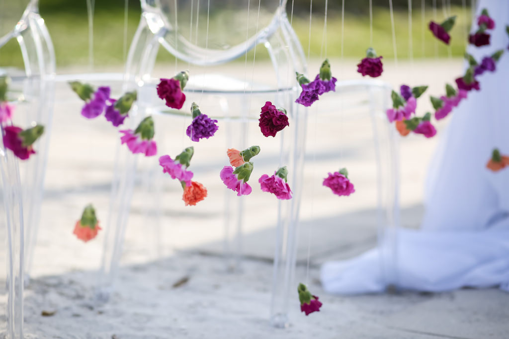 Outdoor Beach Wedding Ceremony Decor with Hanging Pink, Purple, Magenta and Orange Blossoms and Clear Plastic Chairs | Tampa Bay Wedding Rentals and Florist Gabro Event Services | Planner & Designer Kelly Kennedy Weddings and Events
