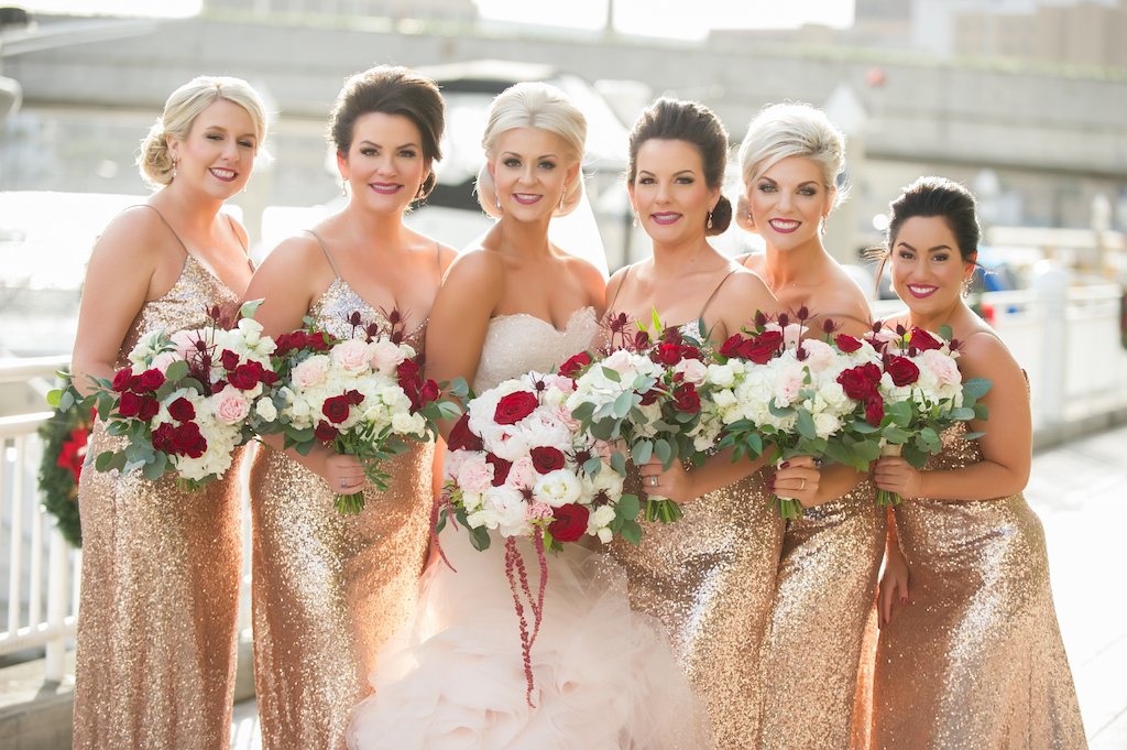 Outdoor Waterfront Bridal Party Portrait, Bridesmaids in Gold Sequin Spaghetti Strap Dresses, Bride iN Strapless Blush Mermaid Dress, with Red and Blush Pink Rose with Greenery Bouquets | Tampa Bay Wedding Photographer Andi Diamond Photography | Hair and Makeup Michele Renee The Studio | Bridesmaids Dress Shop Bella Bridesmaids