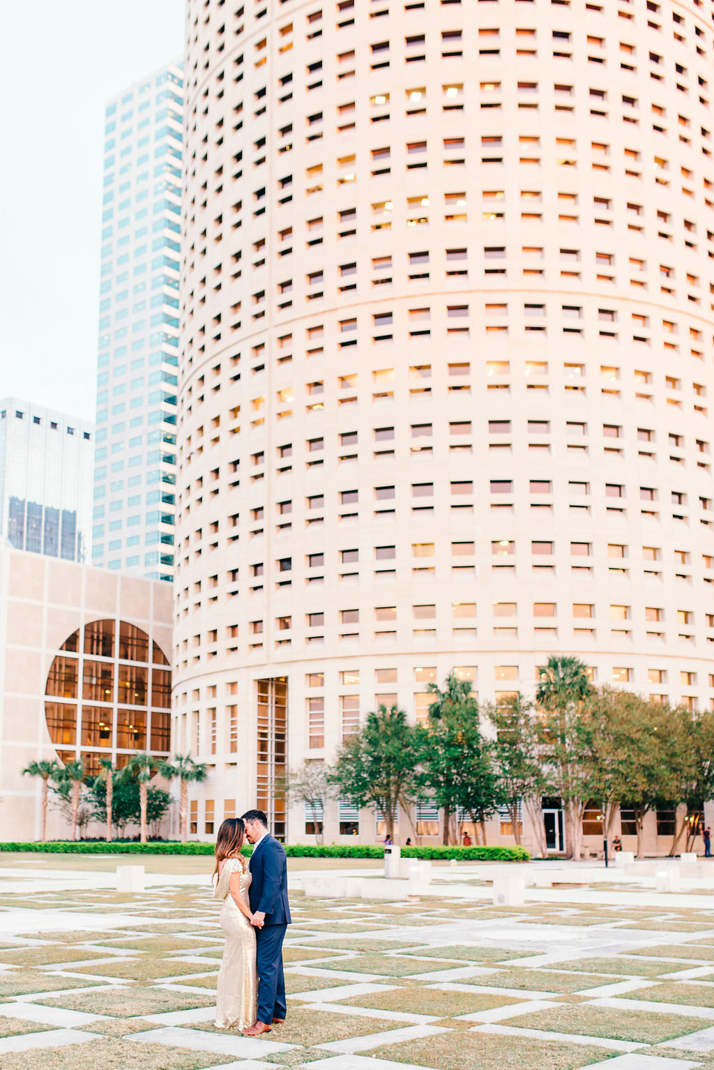 Downtown Tampa Riverwalk Classy Engagement Portrait, Bride in Long Gold Sequin Dress, Groom in Navy Blue Suit with Brown Leather Shoes