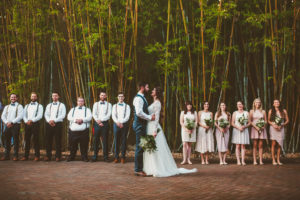 Outdoor Wedding Party Portrait In Bamboo Courtyard Garden, Bridesmaids in Blush Pink with Greenery Bouquets, Groomsmen in White Shirts with Suspenders and Bow Ties, Groom in Navy Blue Vest | Unique Downtown St Pete Wedding Venue NOVA 535