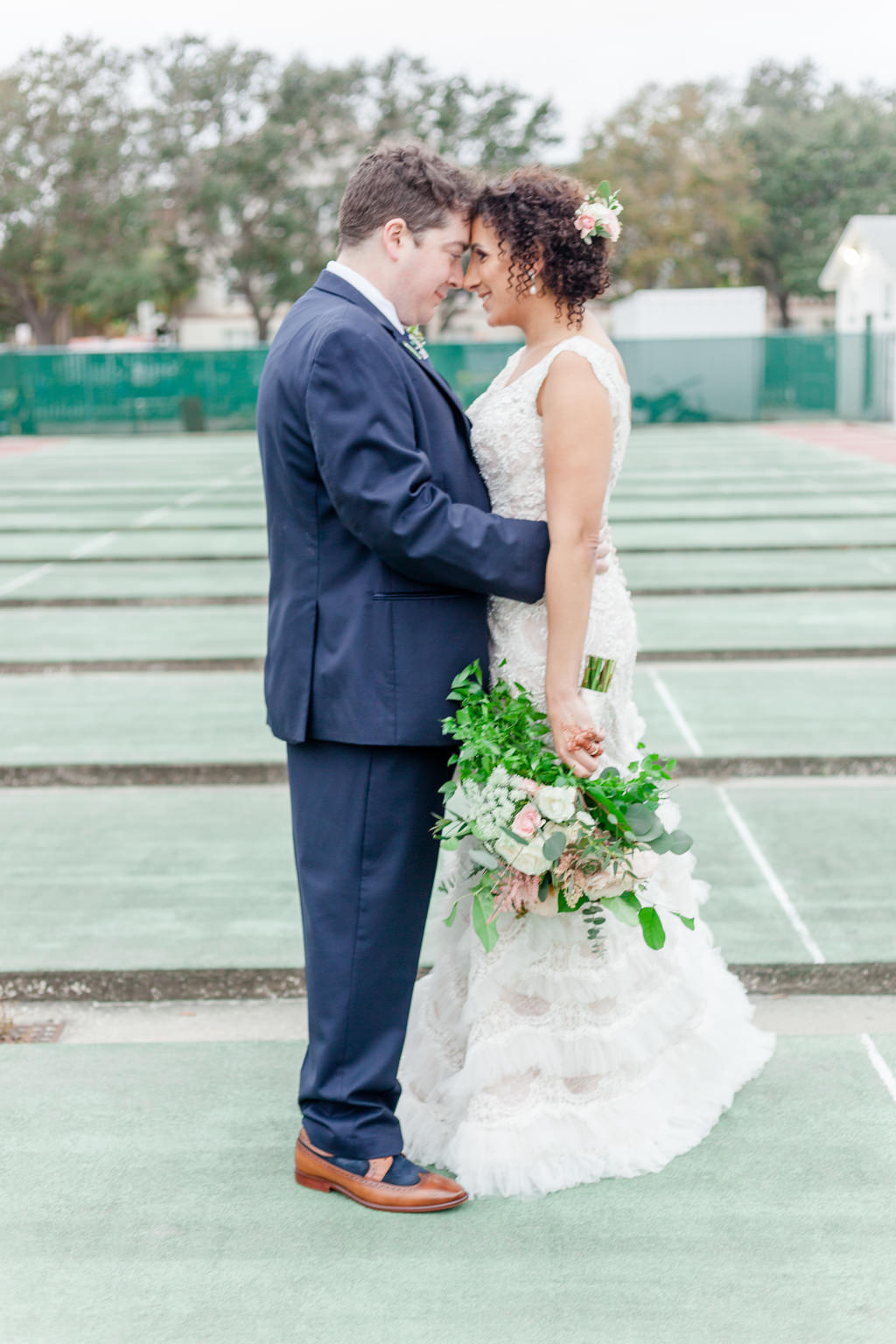 Outdoor Bride and Groom Portrait, Bride in Fringed David's Bridal Dress with Peach and Greenery Bouquet, Groom in Blue Suit with Brown Leather Shoes | Downtown St Pete Historic Wedding Venue The St Petersburg Shuffleboard Club | Tampa Bay Florist Cotton and Magnolia