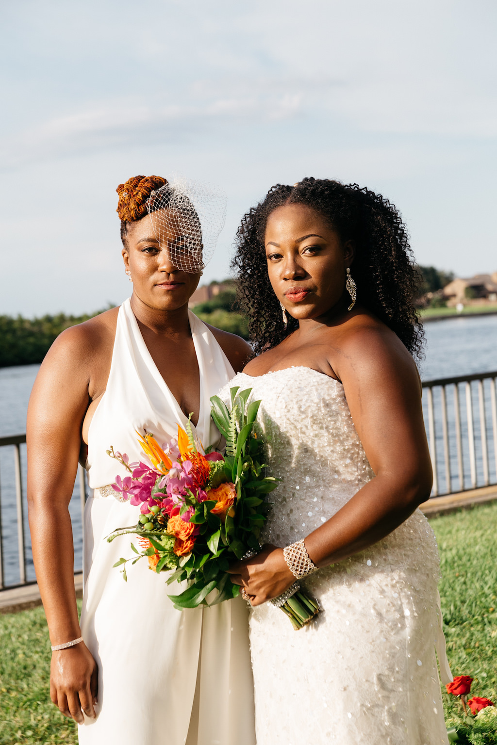 Outdoor Waterfront Wedding Portrait, Bride in Halter BHDLN Pantsuit with Birdcage Veil and Beaded Strapless David's Bridal Dress with Pink, Orange and Red Floral with Tropical Greenery Bouquet | Tampa Waterfront Hotel Wedding Venue DoubleTree Suites by Hilton