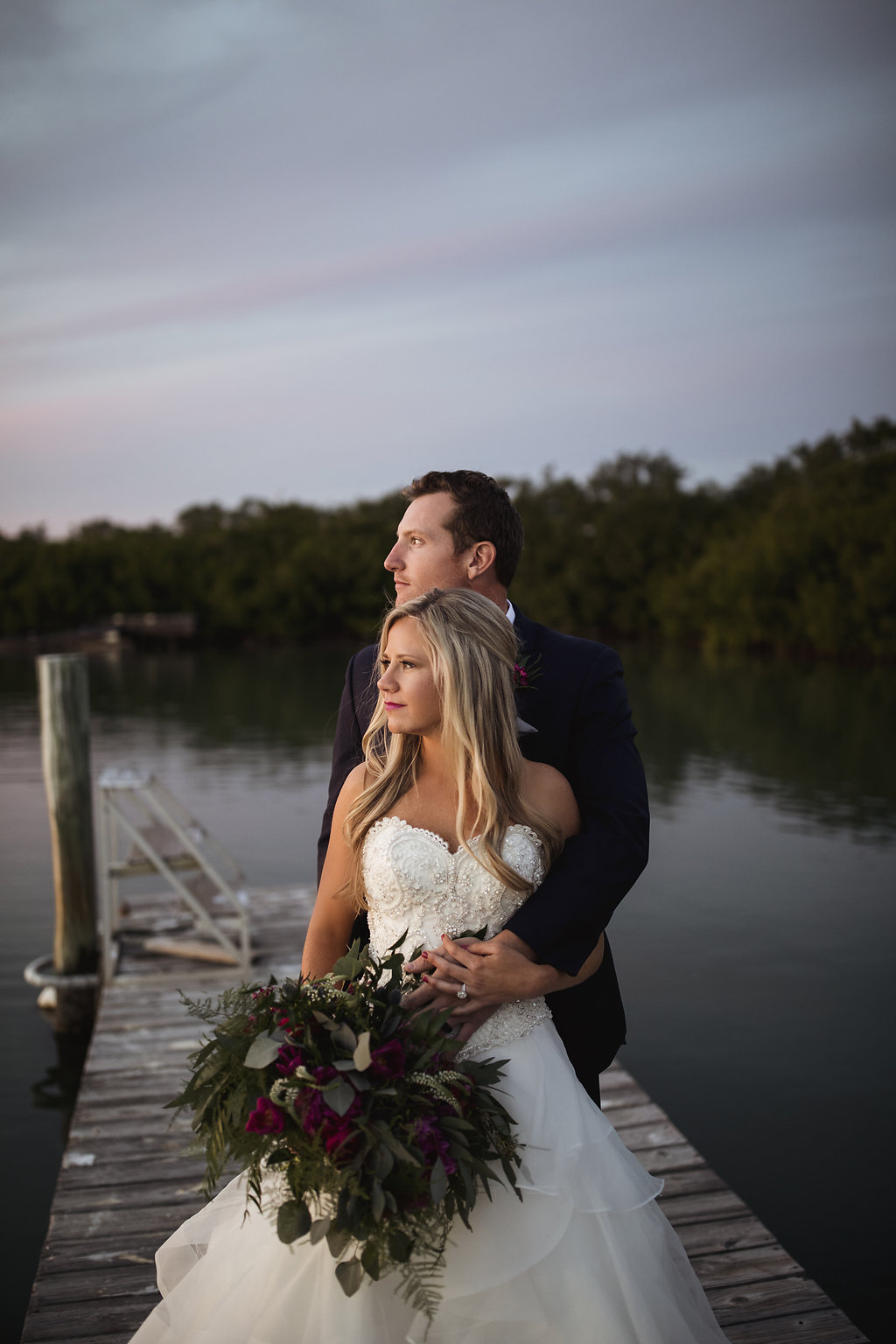 Outdoor Waterfront Dock Wedding Portrait, Bride in Strapless Beaded Layered Ballgown Dress with Fuchsia Floral and tropical Greenery Bouquet | Venue Longboat Island Chapel