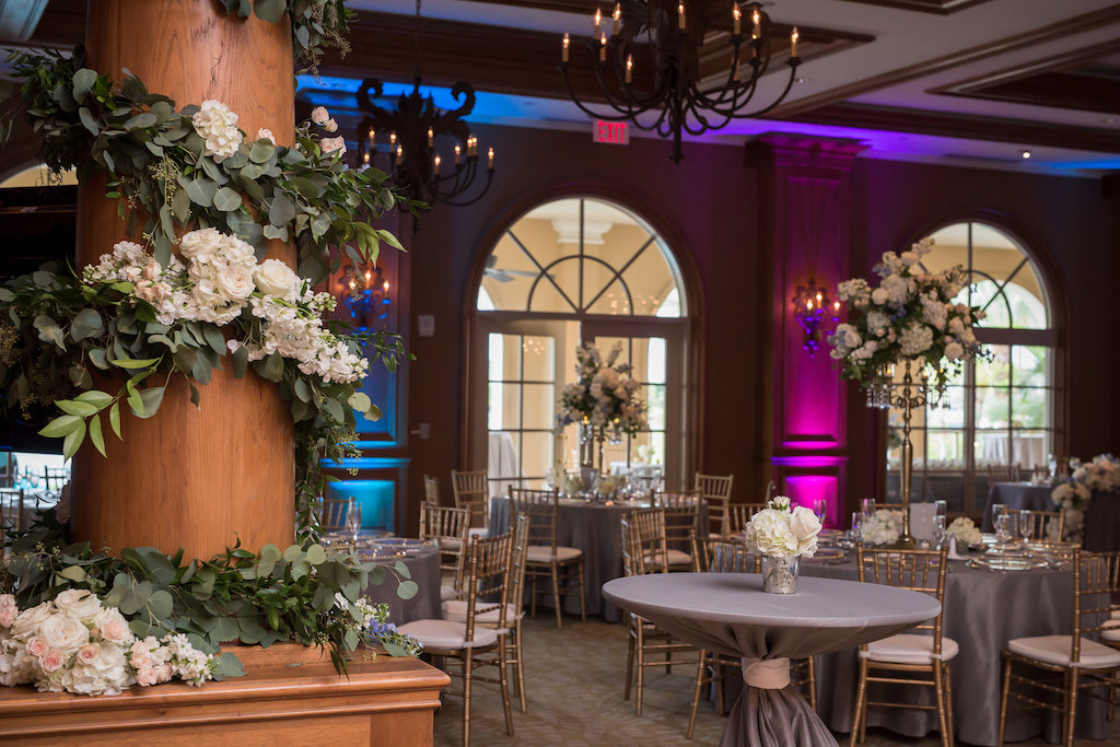 Hotel Ballroom Wedding Reception with White and Blush Floral Greenery Garland Decor, Tall Centerpiece in Silver Candelabra, Gray Silk Linens, Gold Chiavari Chairs, and Blue and Purple Uplighting | Downtown Sarasota Wedding Venue The Ritz Carlton