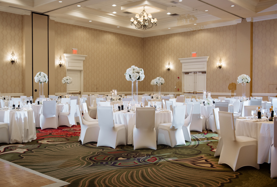 Modern All White Ballroom Wedding Reception Decor with Tall Centerpieces and Spandex Chair Covers