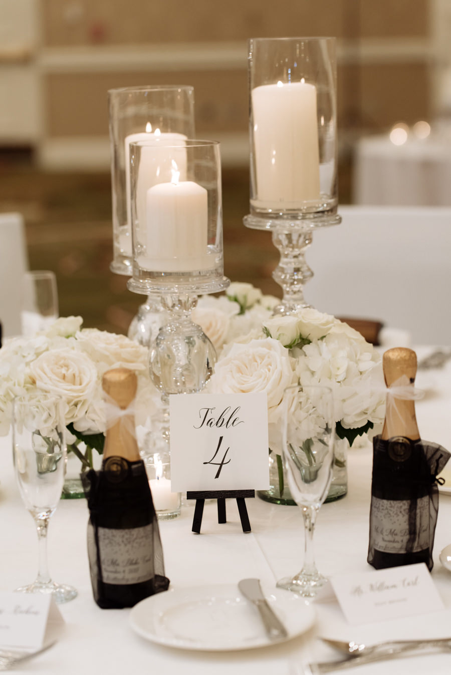 Elegant All White Ballroom Wedding Reception Decor with Candle and Rose Centerpieces and Mini Champagne Favors