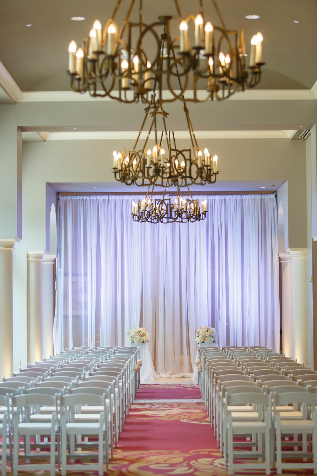 Indoor Hotel Wedding Ceremony with White Folding Chairs, White Florals, and White Draping | Venue The Tampa Renaissance International Hotel