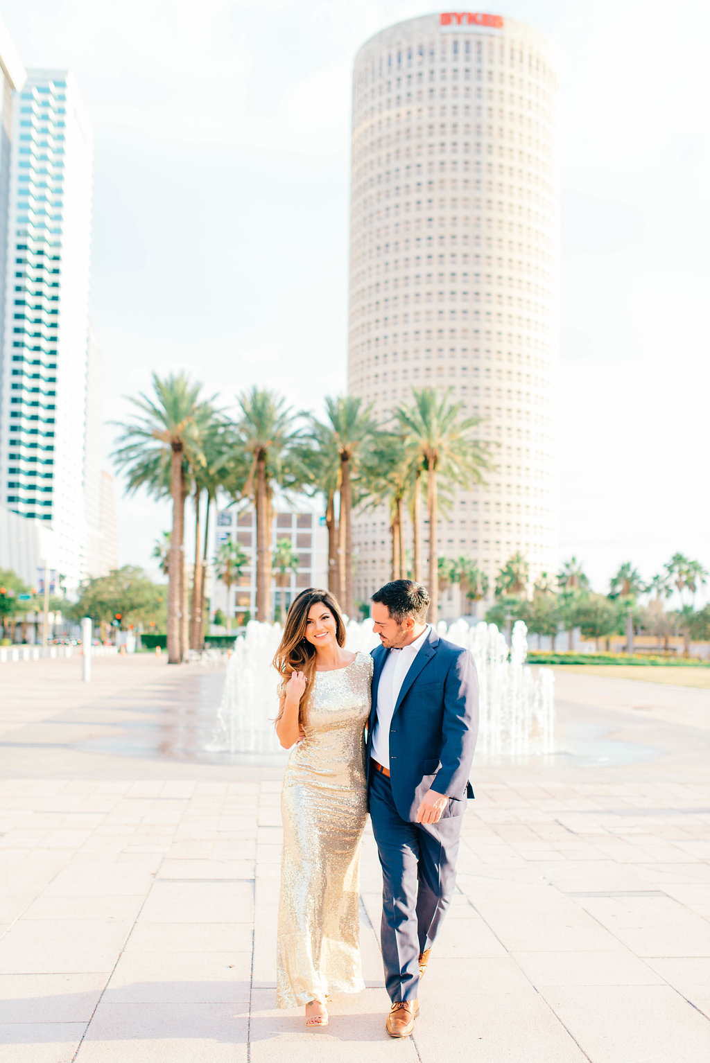 Downtown Tampa Riverwalk Classy Engagement Portrait, Bride in Long Gold Sequin Dress, Groom in Navy Blue Suit with Brown Leather Shoes