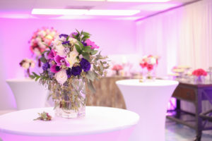 Indoor Wedding Reception Decor with White Stretch Linens, Purple, Pink, and White with Greenery Low Centerpiece in Square Glass Vase | Tampa Bay Wedding Rentals and Florist Gabro Event Services