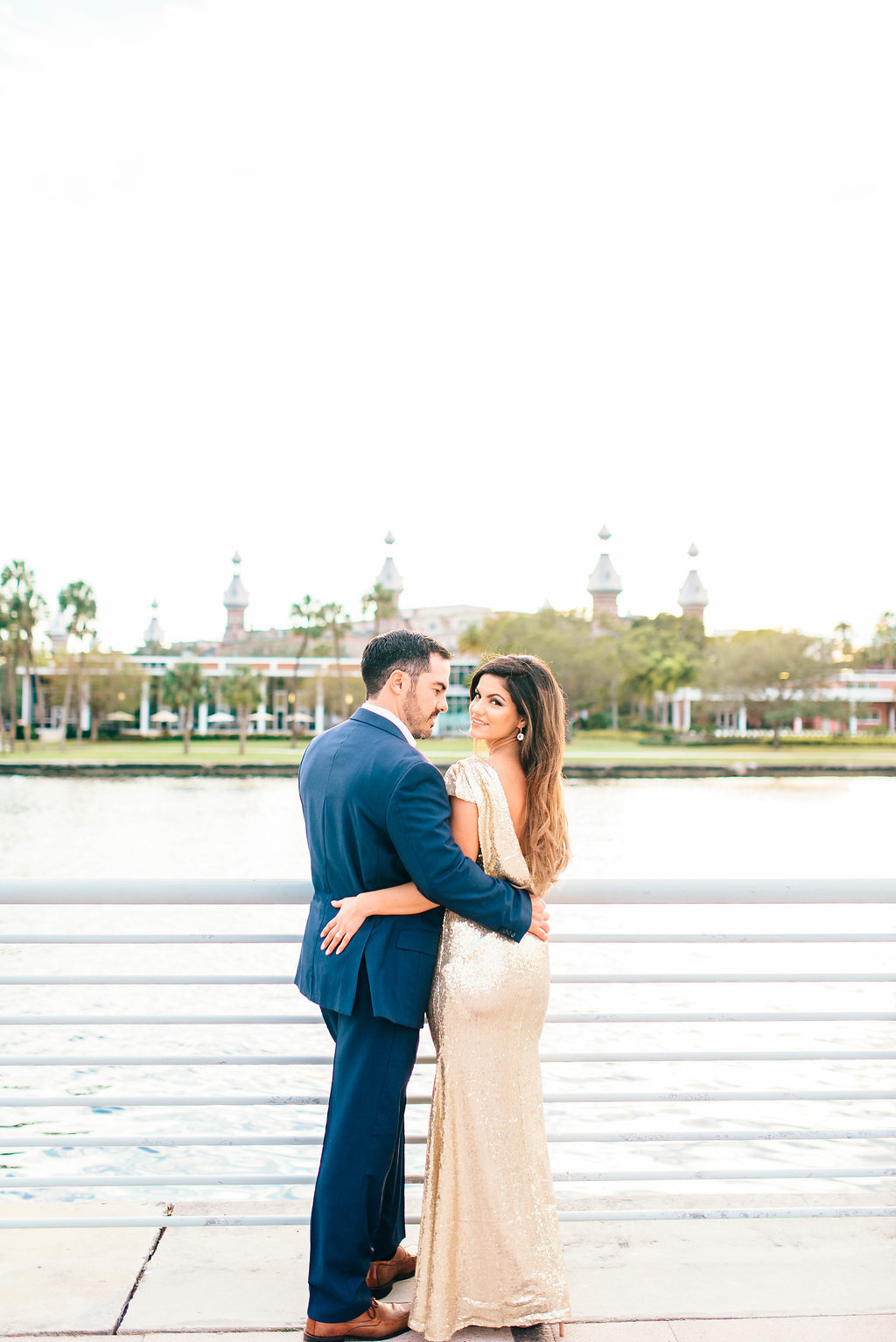 Downtown Tampa Riverwalk Classy Engagement Portrait, Bride in Long Gold Sequin Dress, Groom in Navy Blue Suit with Brown Leather Shoes